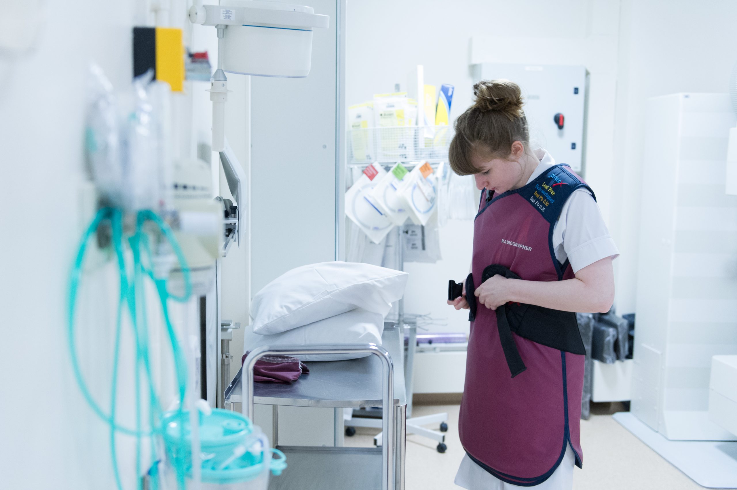 Student Radiographer putting on protective clothing