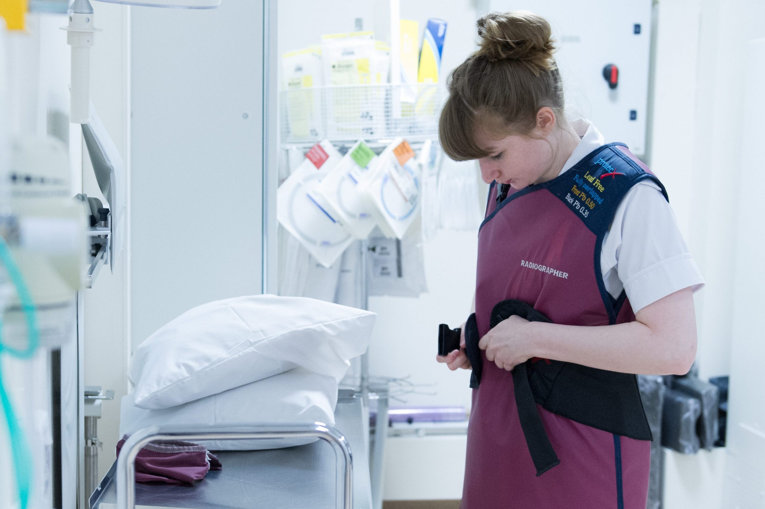 Student Radiographer putting on protective clothing